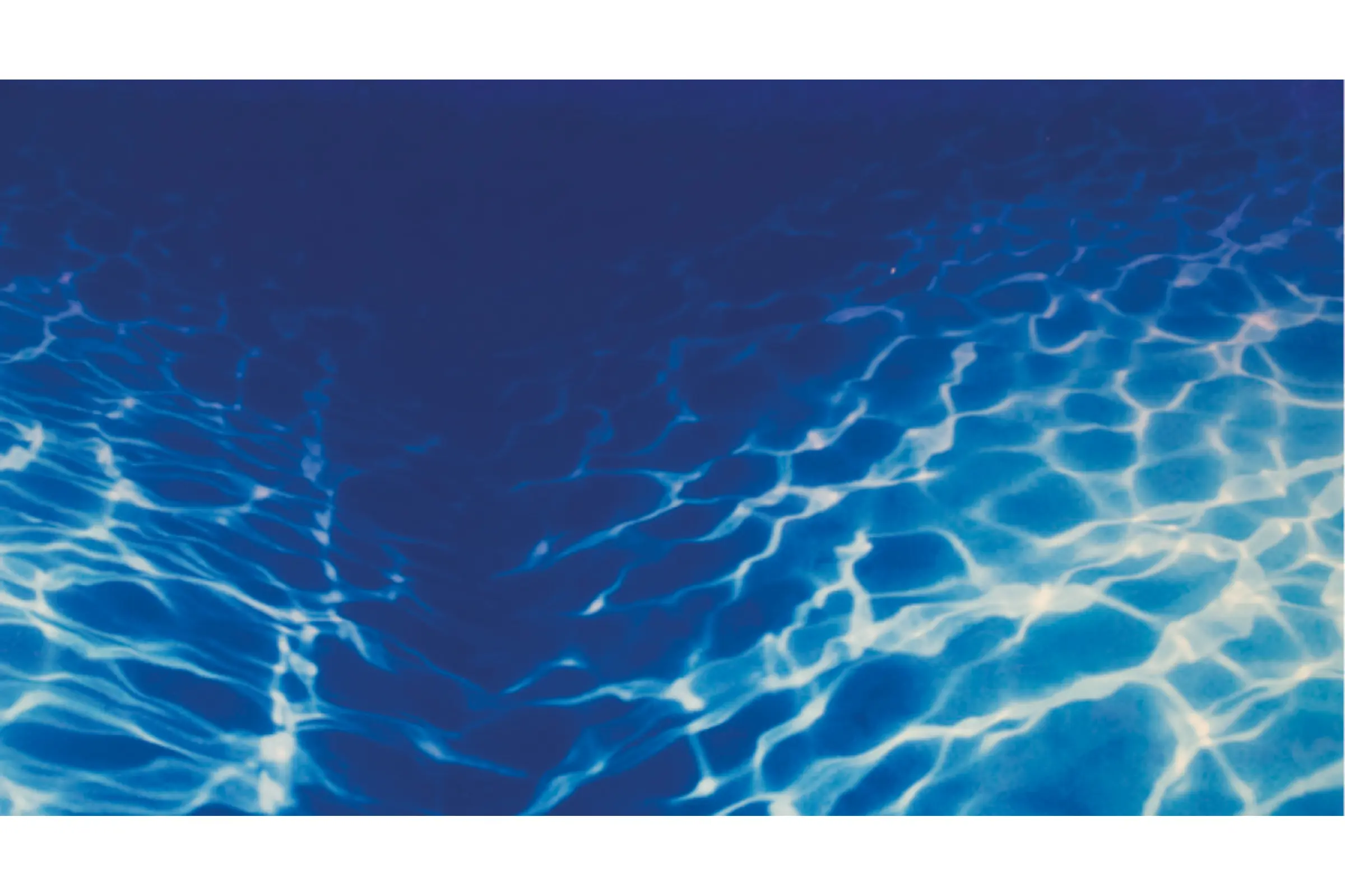 Nahaufnahme von Lichtreflexionen im blauen Wasser eines Schwimmbeckens